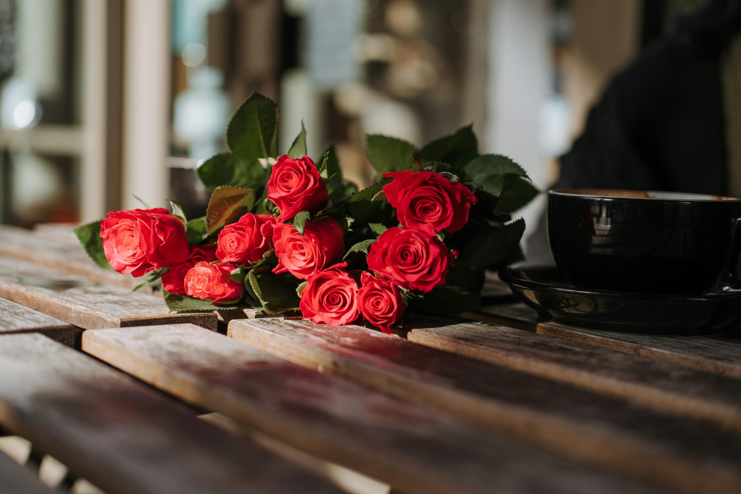A bouquet of fresh red roses placed on a rustic wooden table, capturing natural beauty and elegance.